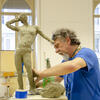 A male adult doing figure sculpting with clay