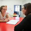Female student sitting at red table with female Italian tutor in Temple University Rome common area